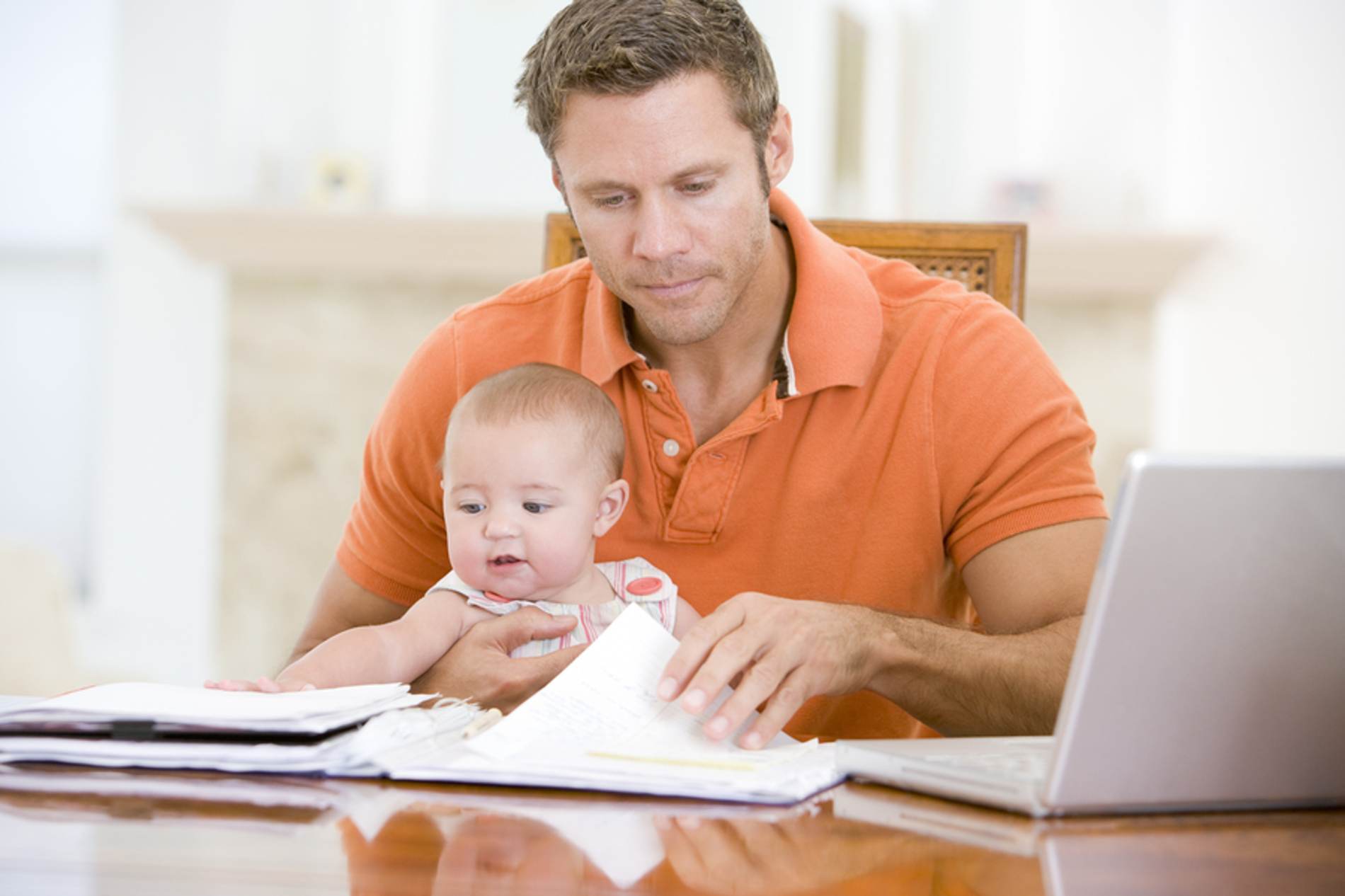 Dad with his baby looking at paperwork at a desk.